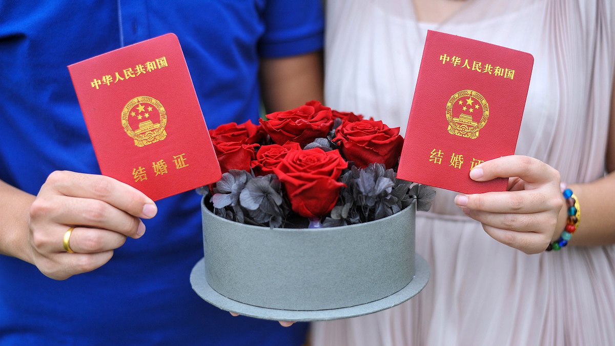 两人手持结婚证与红玫瑰花束，明亮氛围下，徐州领证瞬间，枪花影像