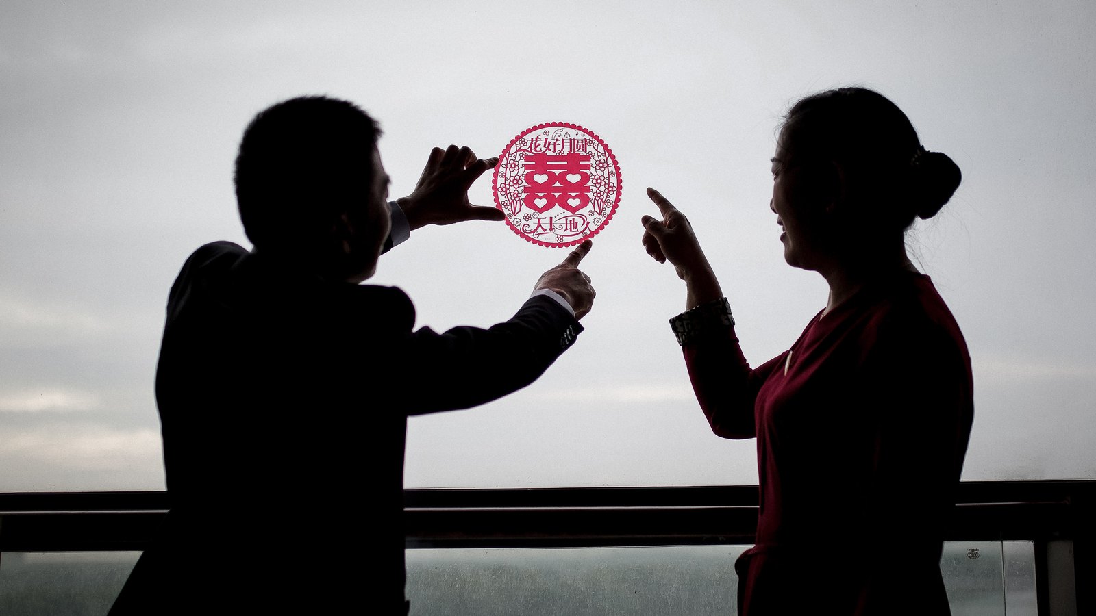 新人与长辈窗前剪影同举囍字剪纸，逆光氛围，淮安婚礼摄影，枪花影像